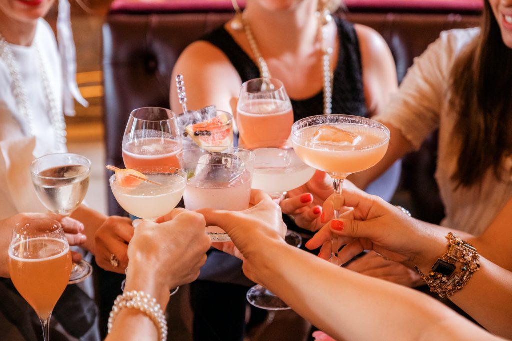 Close up photo of several people holding cocktails in the center of the group. 