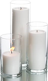 Photograph of three white candles of various sizes in glass holders that are taller than the candles to protect the flame from wind. 