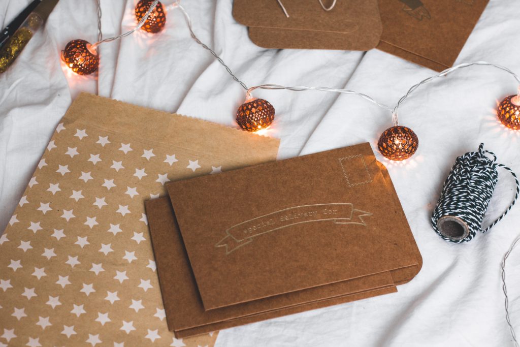 Photo of brown paper gift card envelopes on a white cloth surface with string lights and package string  